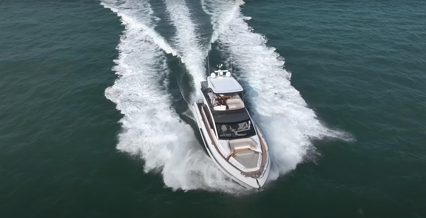 A luxury motorboat speeds through turquoise waters, leaving a wake as it navigates the ocean.